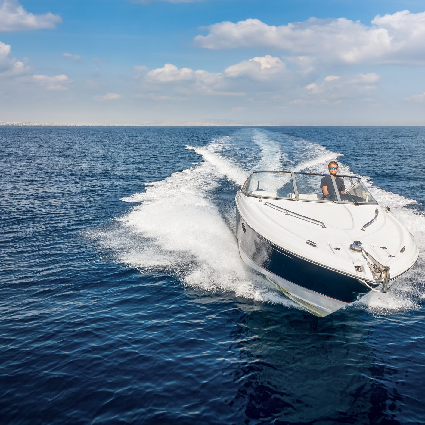 Aerial front view of a sports motor boat cruising with high speed over the blue sea