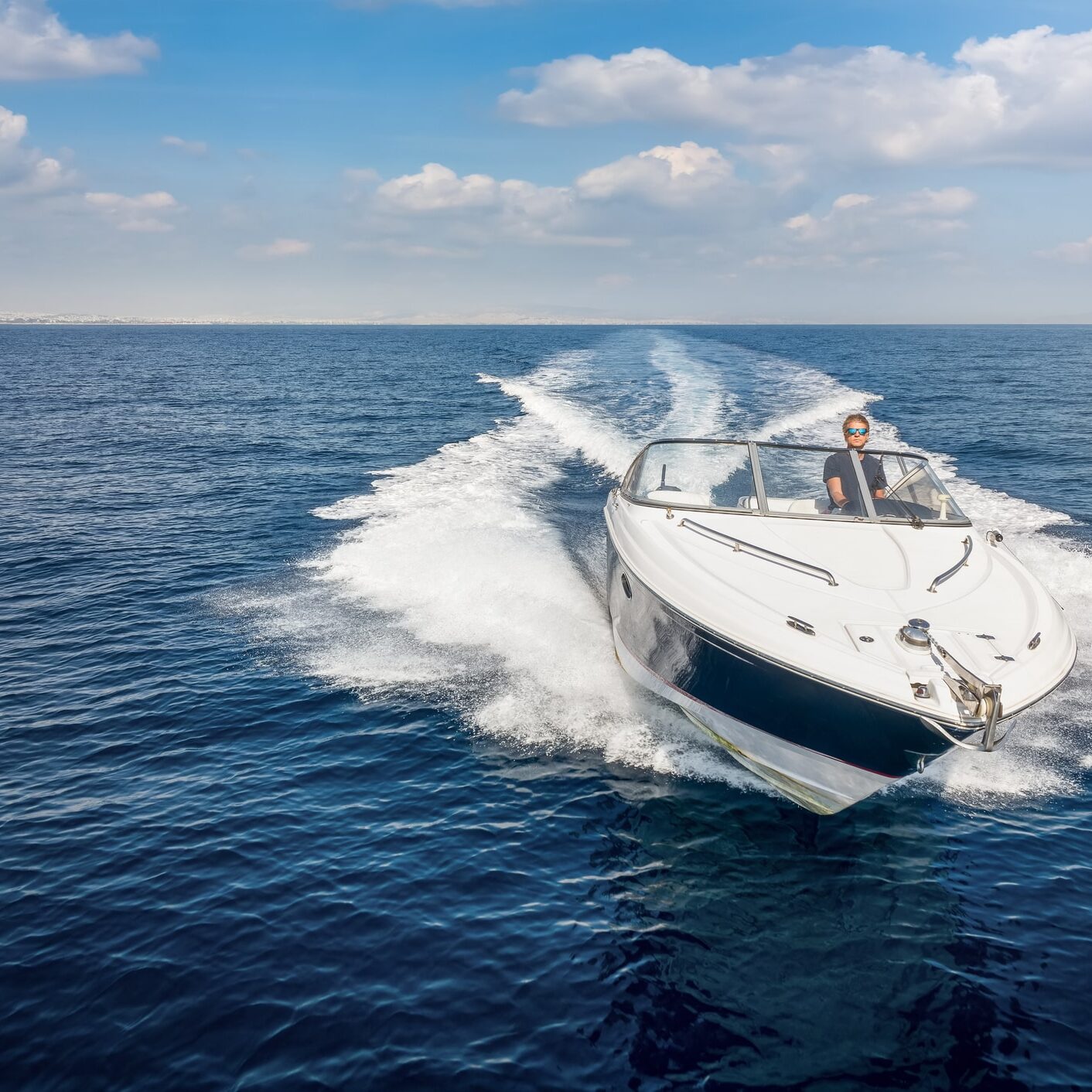 Aerial front view of a sports motor boat cruising with high speed over the blue sea